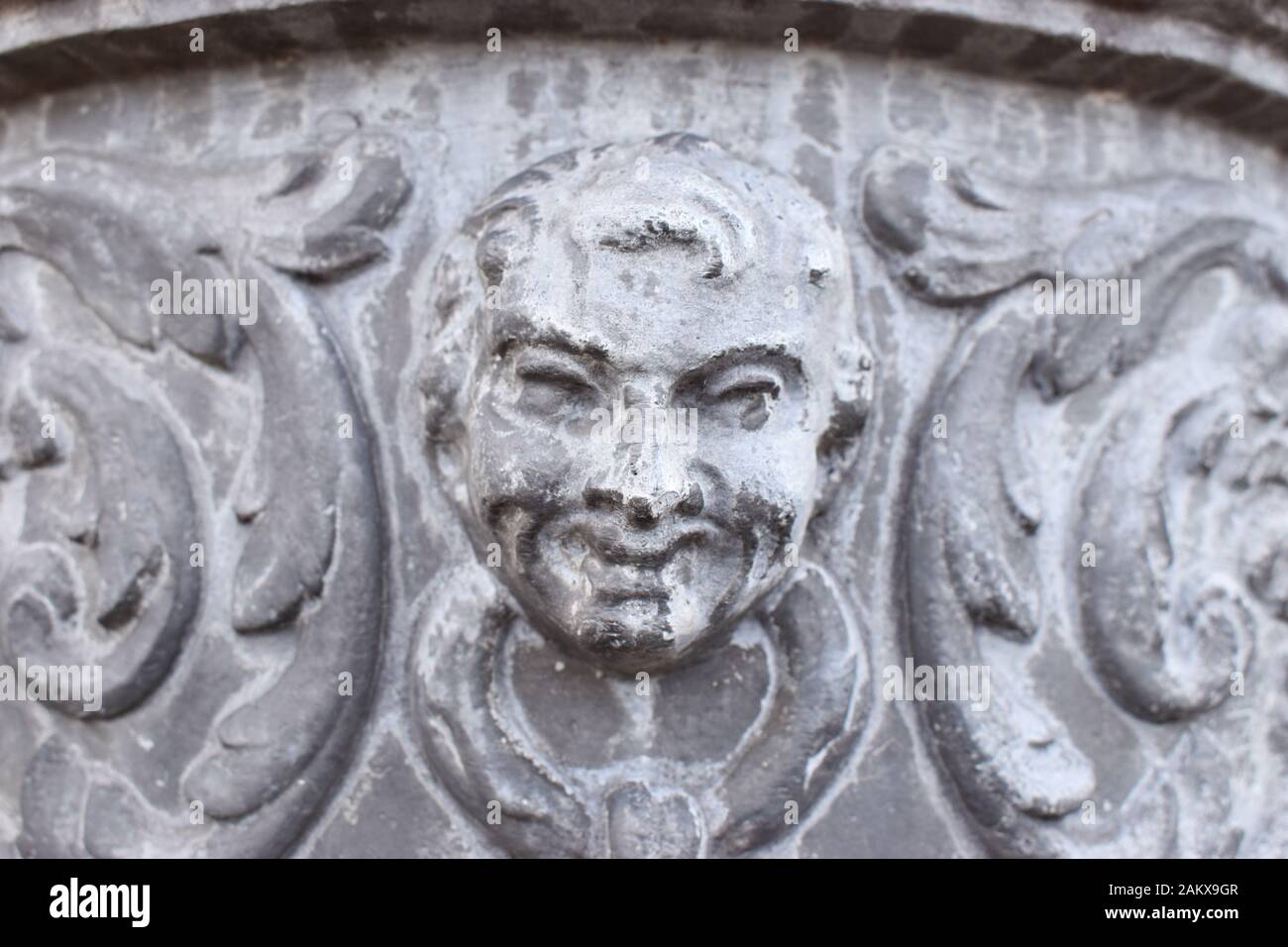 Una scultura in pietra di un volto mans su un'urna Foto Stock