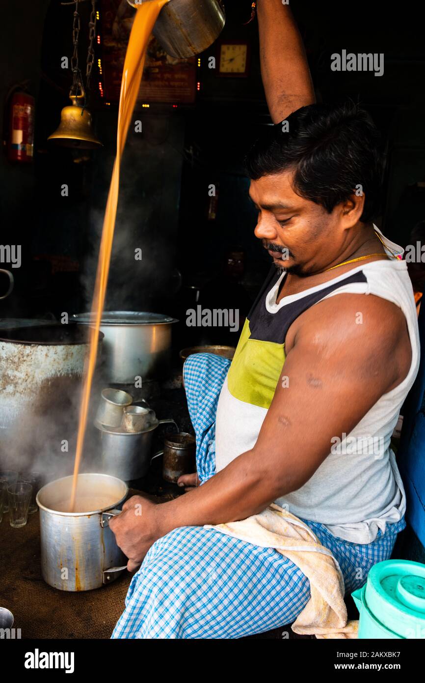 Latte zuccherato tè è largamente consumato in Kolkata preparata dal locale di fornitori di tè da mattina fino a notte come questo tè venditore è versando il tè da una pentola Foto Stock
