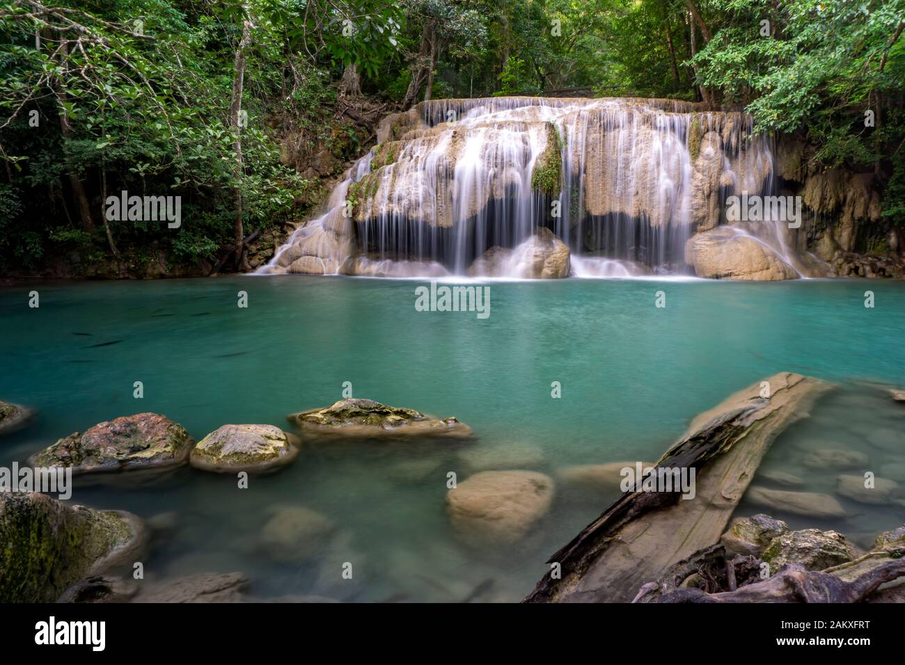 Pulite acque verde smeraldo dalla cascata circondata da alberi piccoli - grandi alberi, colore verde, Erawan cascata, la provincia di Kanchanaburi, Thailandia Foto Stock