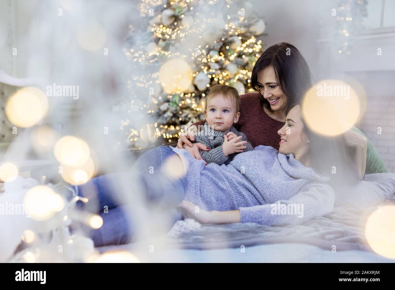 Giovane donna, sua madre e figlio di bambino che gode il tempo tranquillo vicino all'albero di Natale a casa Foto Stock