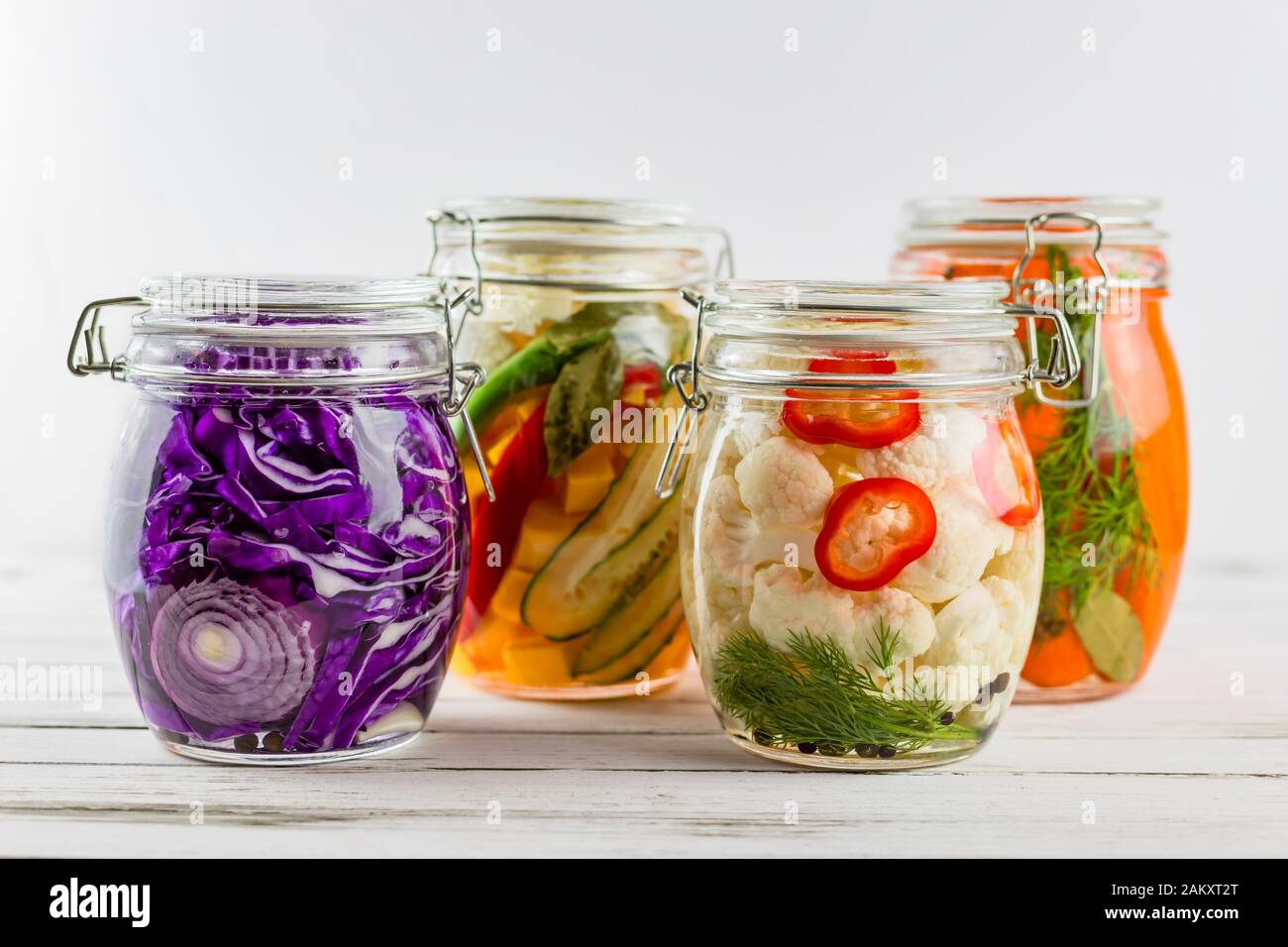 vasi di vetro di cavolo rosso fermentato, cavolfiore, carote, verdure su un fondo leggero. fermentazione è una fonte di probiotics. Foto Stock