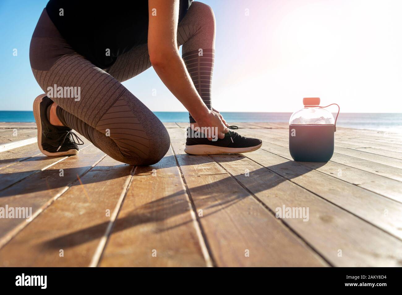 Guida femmina facendo il suo lacci delle scarpe, all'aperto sotto il sole Foto Stock