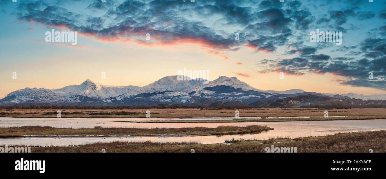Maestosa immagine del paesaggio di Snowdonia montagne innevate con suggestive nuvole al tramonto e bella luce vibrante Foto Stock