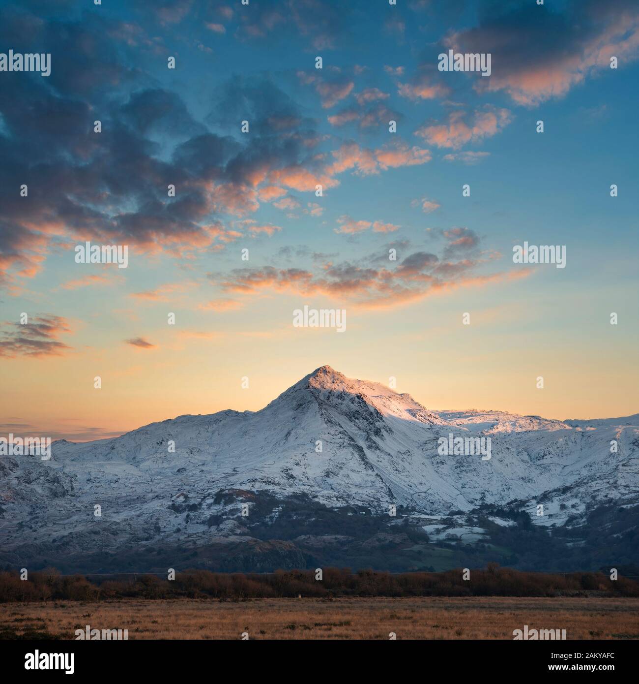 Maestosa immagine del paesaggio di Snowdonia montagne innevate con suggestive nuvole al tramonto e bella luce vibrante Foto Stock