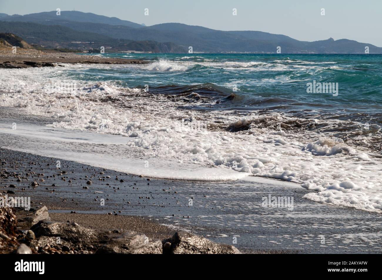 Vista panoramica sulla costa con spiaggia di ciottoli e onde d'acqua sul lato ovest dell'isola greca di Rodi tra Kamiros e Mandriko Foto Stock