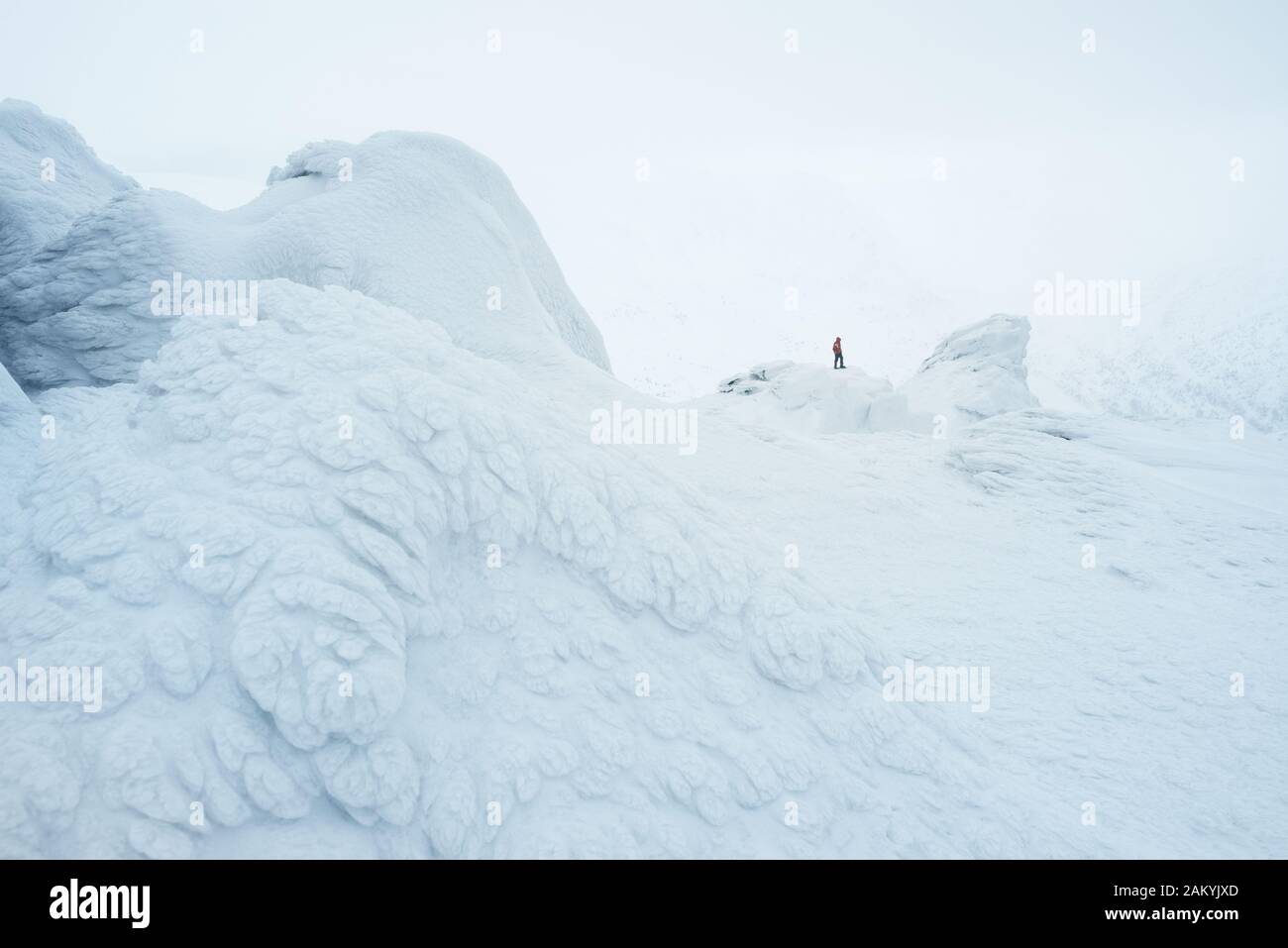 Paesaggio bianco neve con un climber in montagna. Pittoresco brina sulle rocce nella nebbia Foto Stock