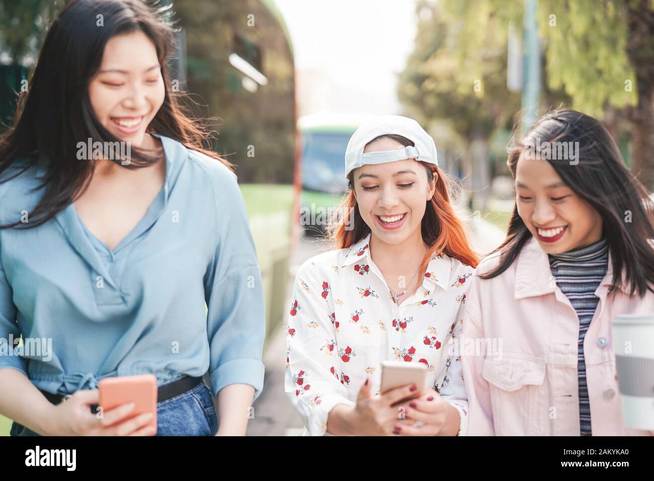 Amici asiatici felici camminare in città mentre si guarda su smartphone mobili - giovani ragazze adolescenti divertirsi con nuove app di social media Foto Stock