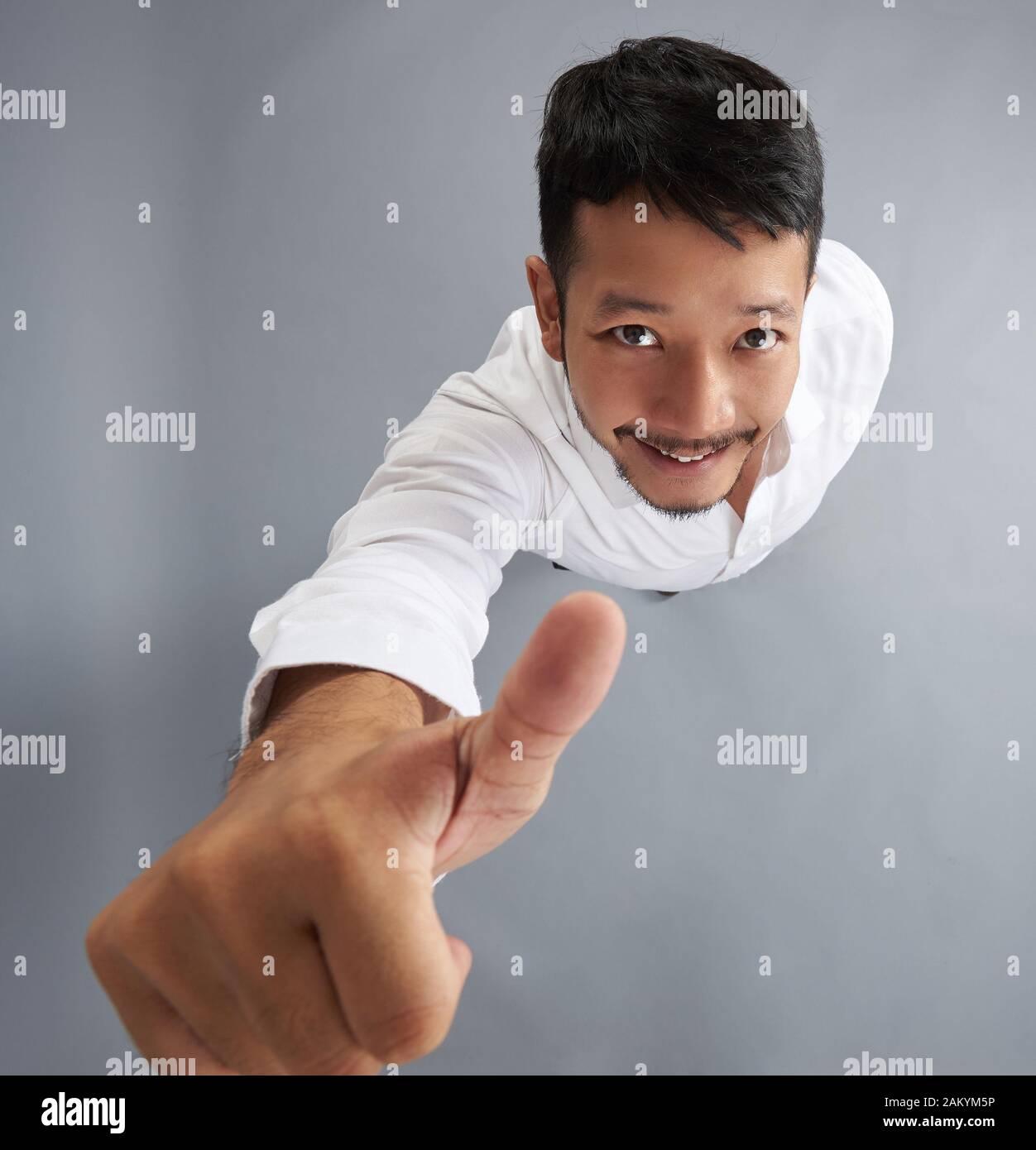 Giovane uomo asiatico mostrano il pollice al di sopra vista dall'alto su grigio di sfondo per studio Foto Stock