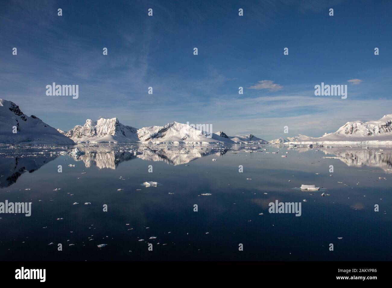 Paesaggio antartico, mare, ghiaccio, ghiacciai e montagne si riflettono nell'oceano in una luminosa giornata di sole Foto Stock