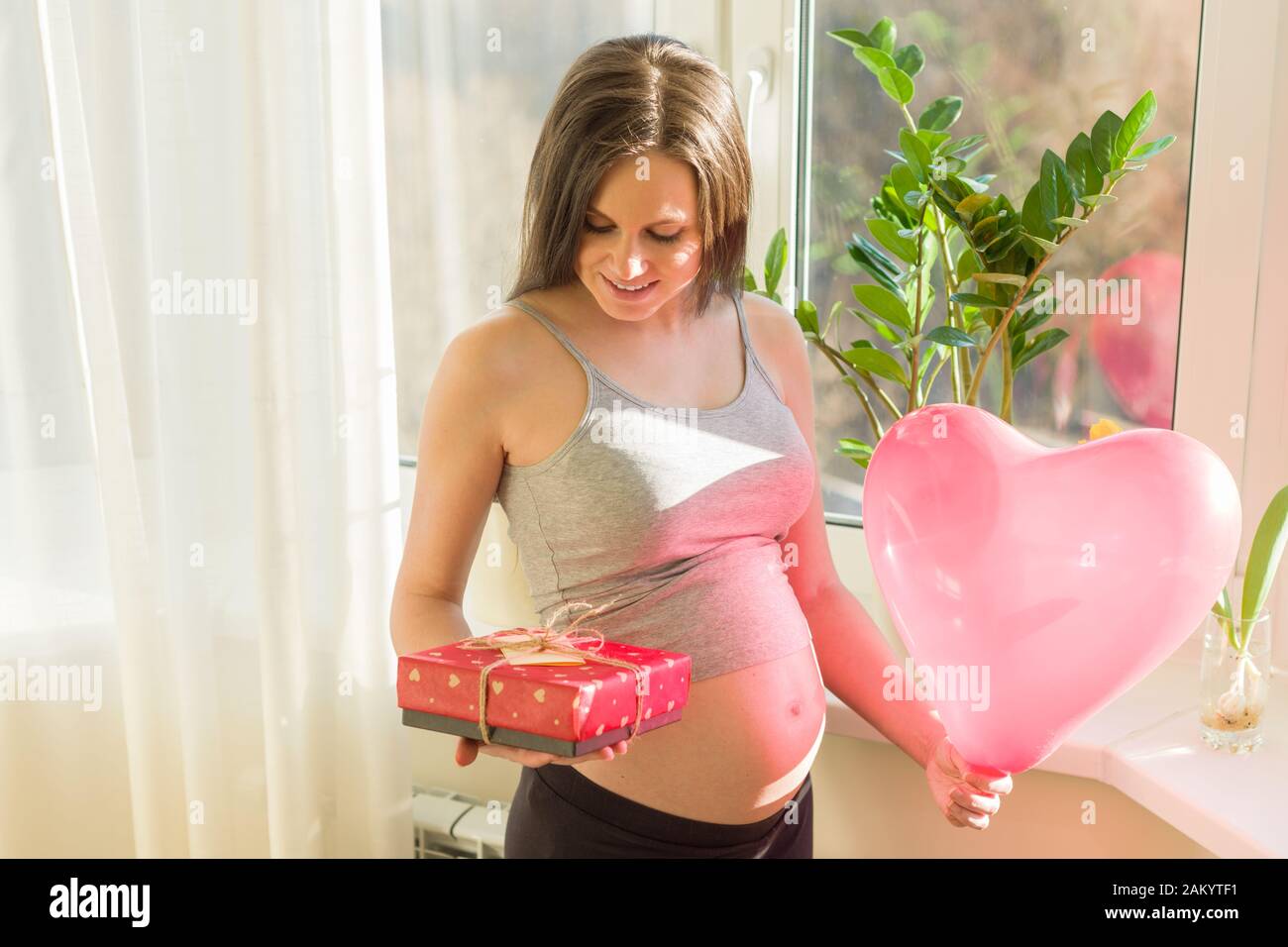 Felice giovane bella donna incinta con scatola regalo e palloncino cuore  rosso, regalo per San Valentino, per le vacanze di primavera. Maternità e  gravidanza Foto stock - Alamy