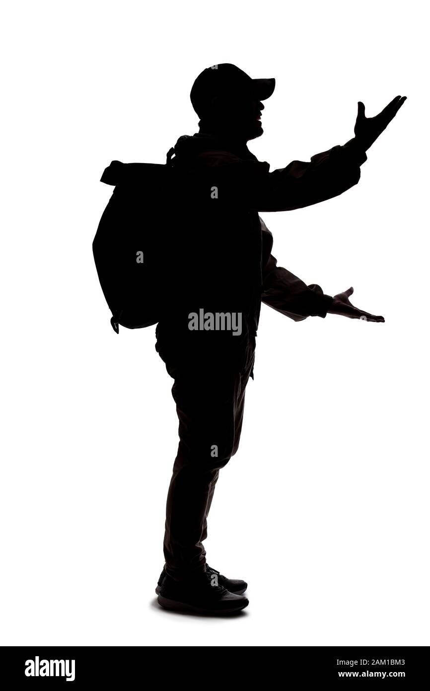 Silhouette di uomo che indossa uno zaino che sembra un viaggiatore o trekking escursionistico. Sta gesturando come sta parlando o sta parlando Foto Stock