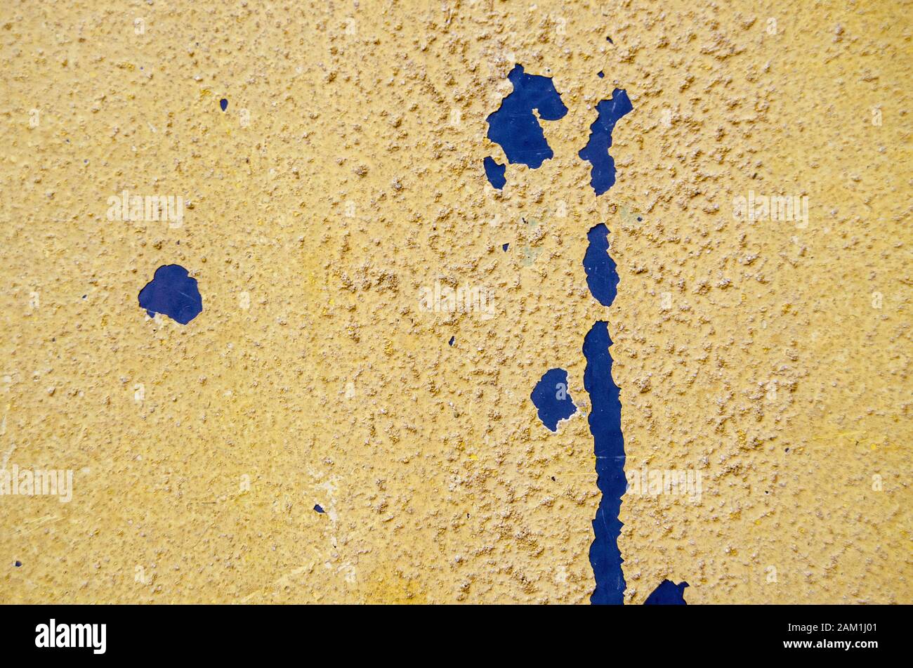 Screpolatura e distacco della vernice gialla testurizzata per rivelare una mano di fondo blu. Foto Stock