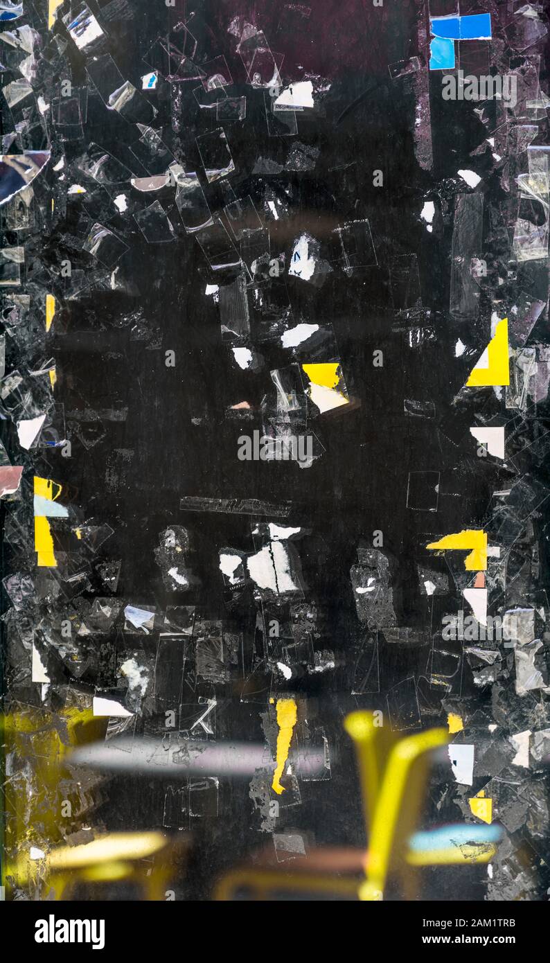 Un frammento della superficie di vetro colorato sulla porta anteriore con i resti di un nastro adesivo trasparente e scarti di poster pubblicitari e annunci pubblicitari Foto Stock