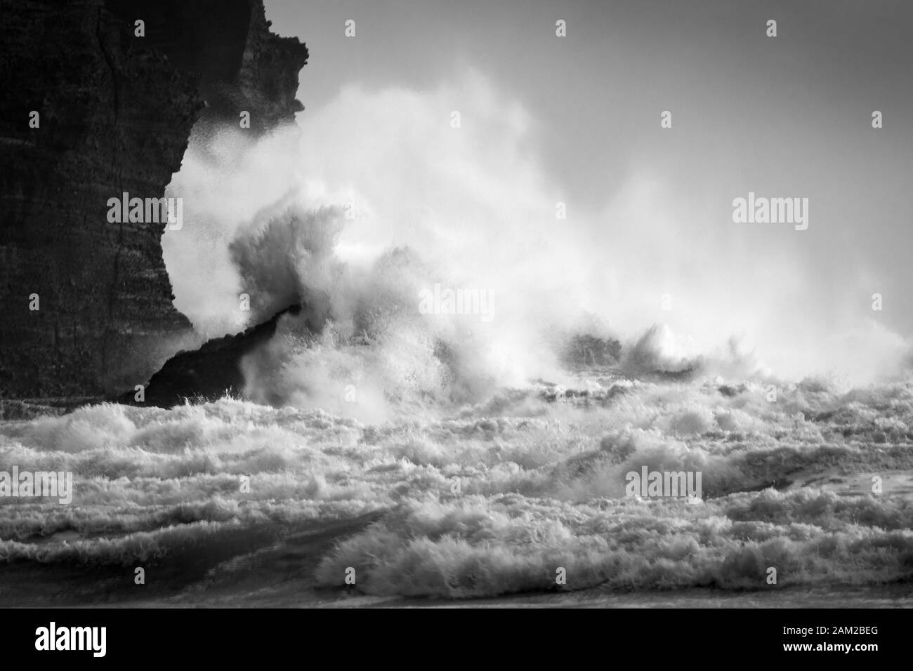 Immagine in bianco e nero di grandi onde che si infrangono contro le rocce di Piha Beach, Waitakere, Nuova Zelanda Foto Stock