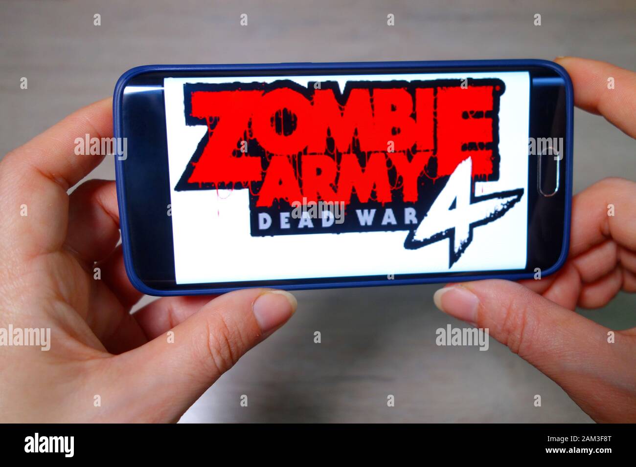 Ucraina, Berdyansk - 24 dicembre: Mani tenere il telefono con il gioco incluso Zombie Army 4. Foto Stock