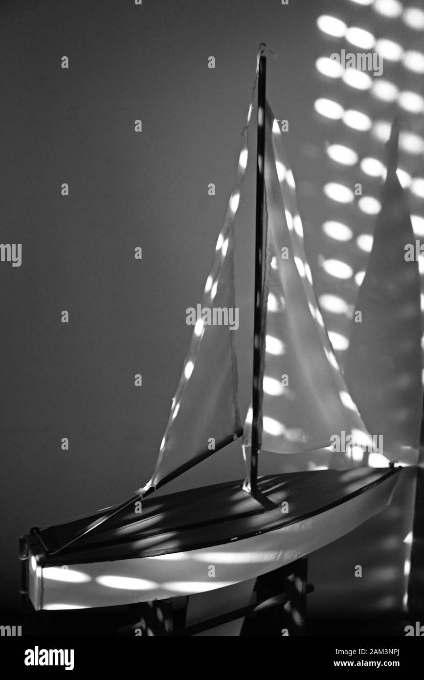 Modello in scala di una barca a vela in legno illuminata da luce proveniente da una serranda. Foto Stock
