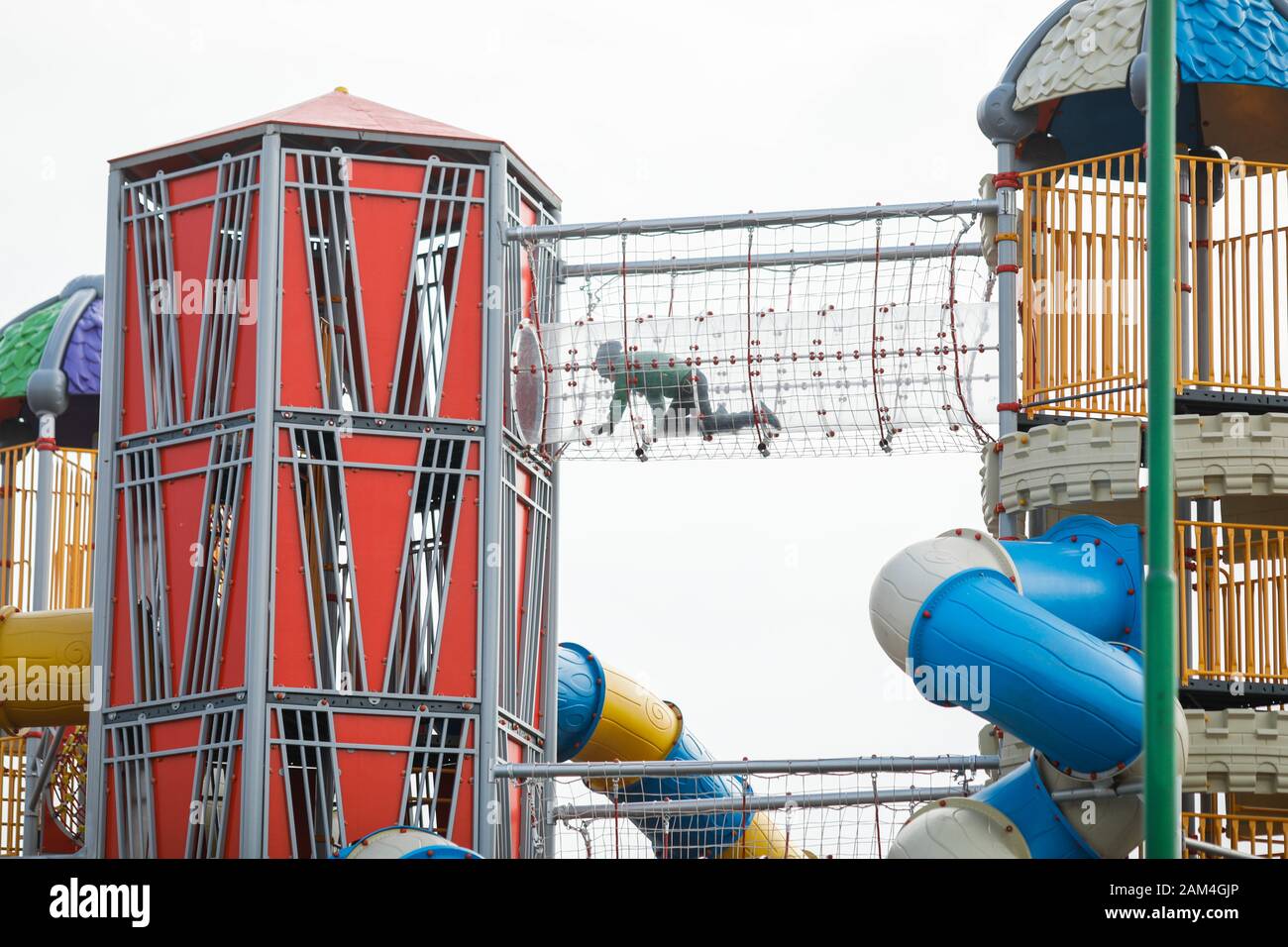 I bambini che strisano all'interno di un tubo trasparente in un colorato parco giochi per bambini Foto Stock