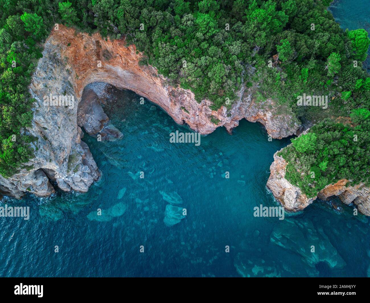 Vista aerea di una ripida scogliera, natura incontaminata della costa del Montenegro. Grotte Marine e insenature alternate sulla costa mediterranea Foto Stock