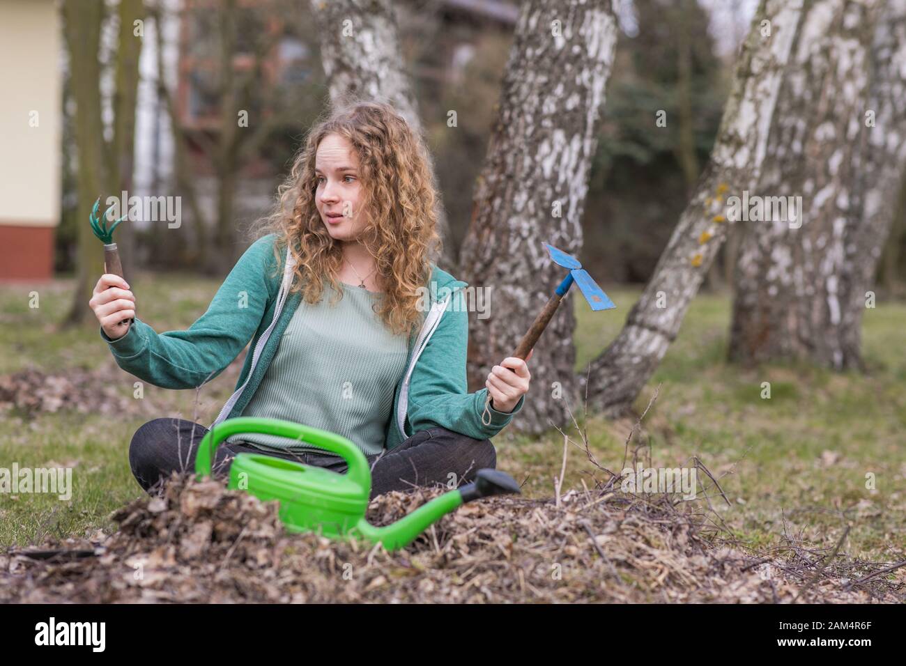 Giovane donna sorpresa durante la pulizia di primavera nel giardino Foto Stock