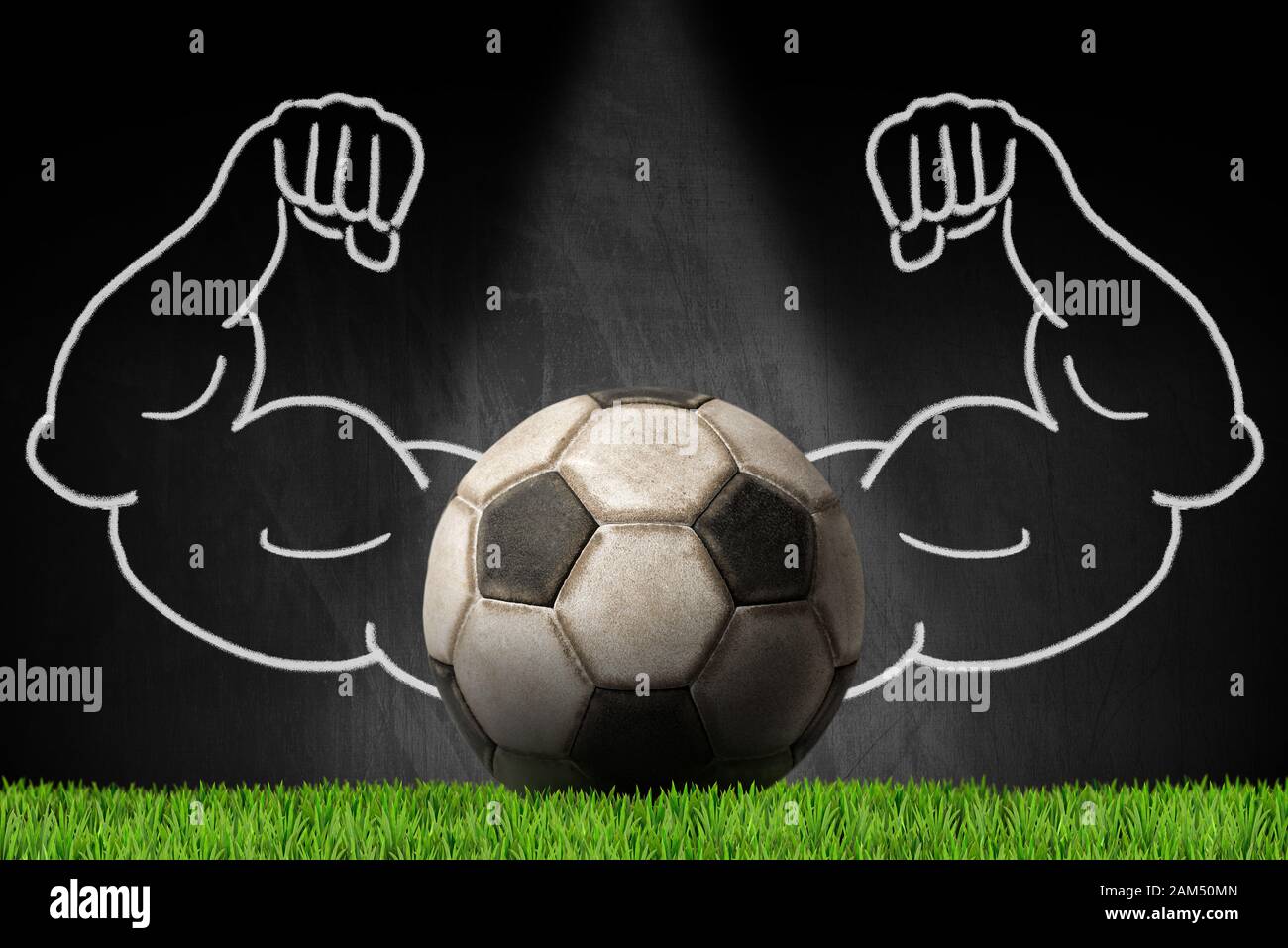 Vecchia palla da calcio in pelle su una lavagna con braccia muscolari, erba verde e spazio copia Foto Stock