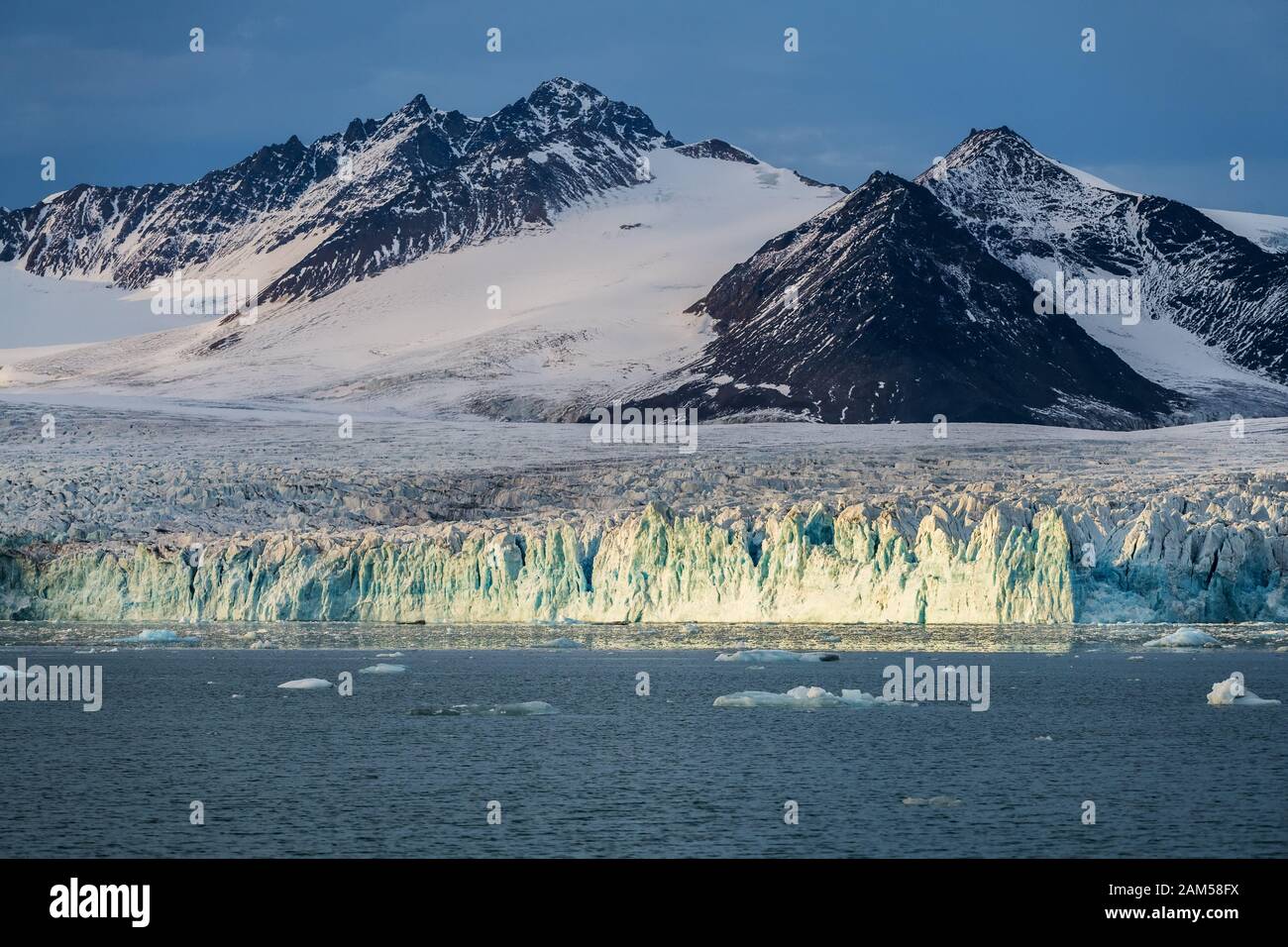 Ghiacciaio blu di fronte alla catena montuosa rocciosa - paesaggio panoramico dell'Artico Foto Stock