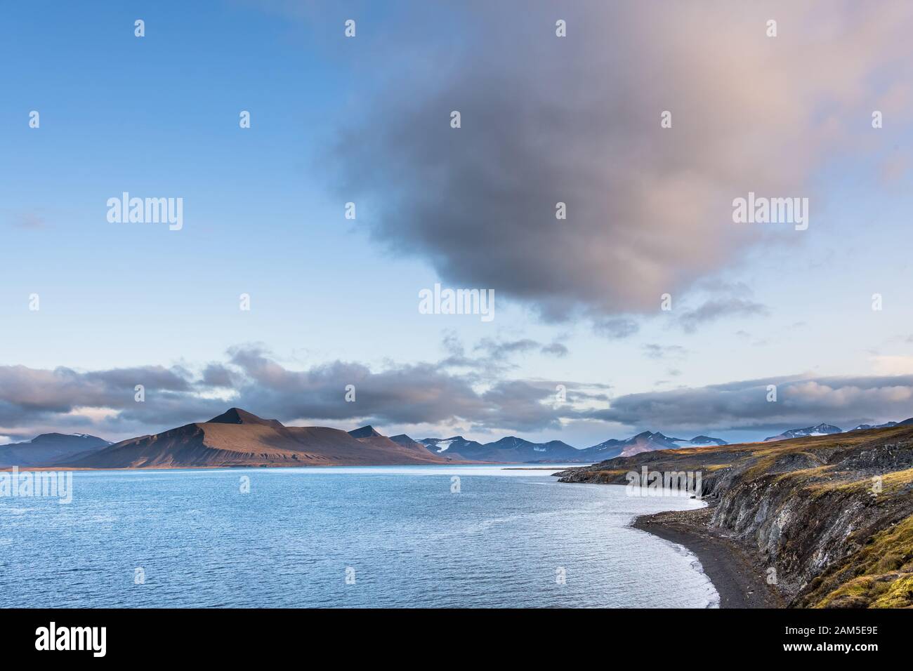 Vista sull'oceano con catena montuosa e grande nube nel cielo - incredibile paesaggio nell'Artico Foto Stock