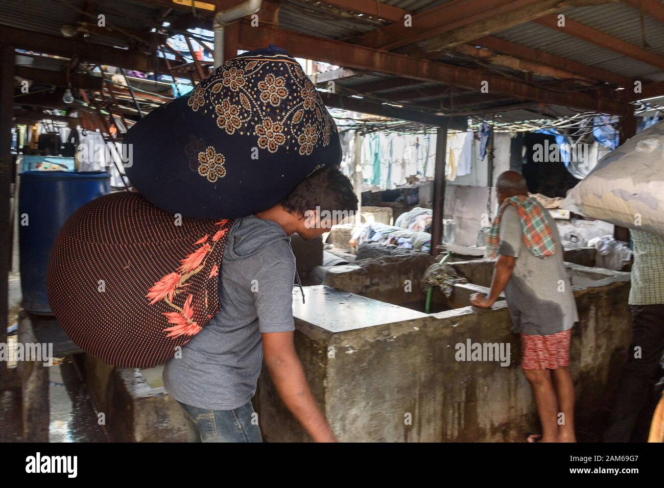 Indian woker portare borse di vestiti a Dhobi Ghat è lavanderia all'aperto a Mumbai. India Foto Stock