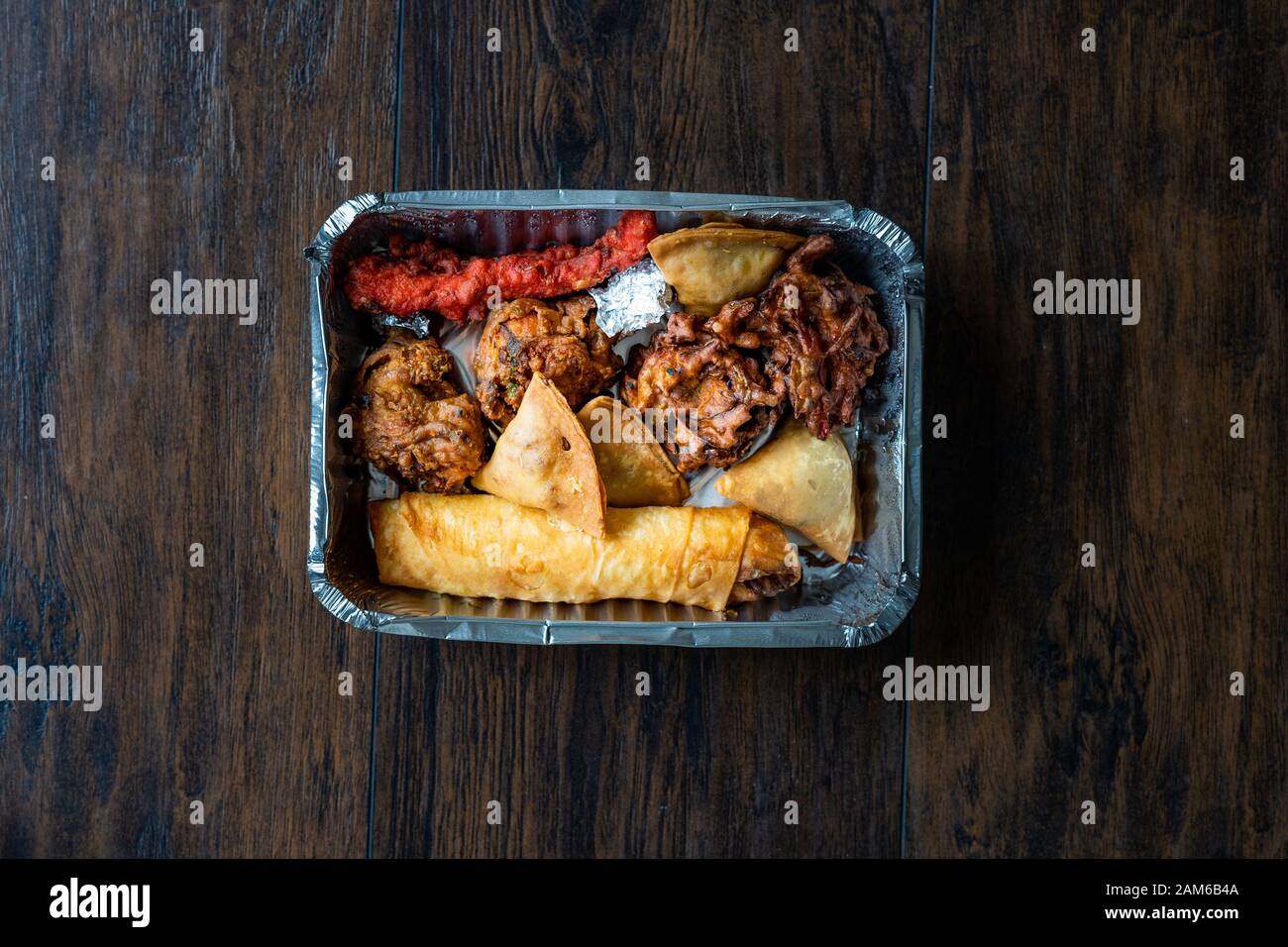 Tenere lontano il cibo indiano piastra con pollo, Pakora, Aloo Tikki, Samosas Samsa e involtini primavera in contenitore di plastica Box / pacchetto. I cibi tradizionali. Foto Stock