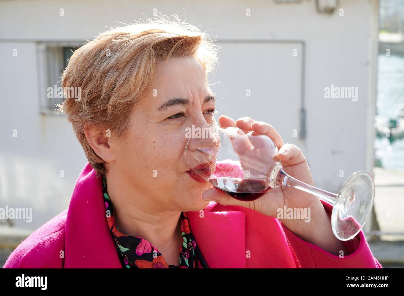 Donna bionda di media età che beve vino rosso Foto Stock