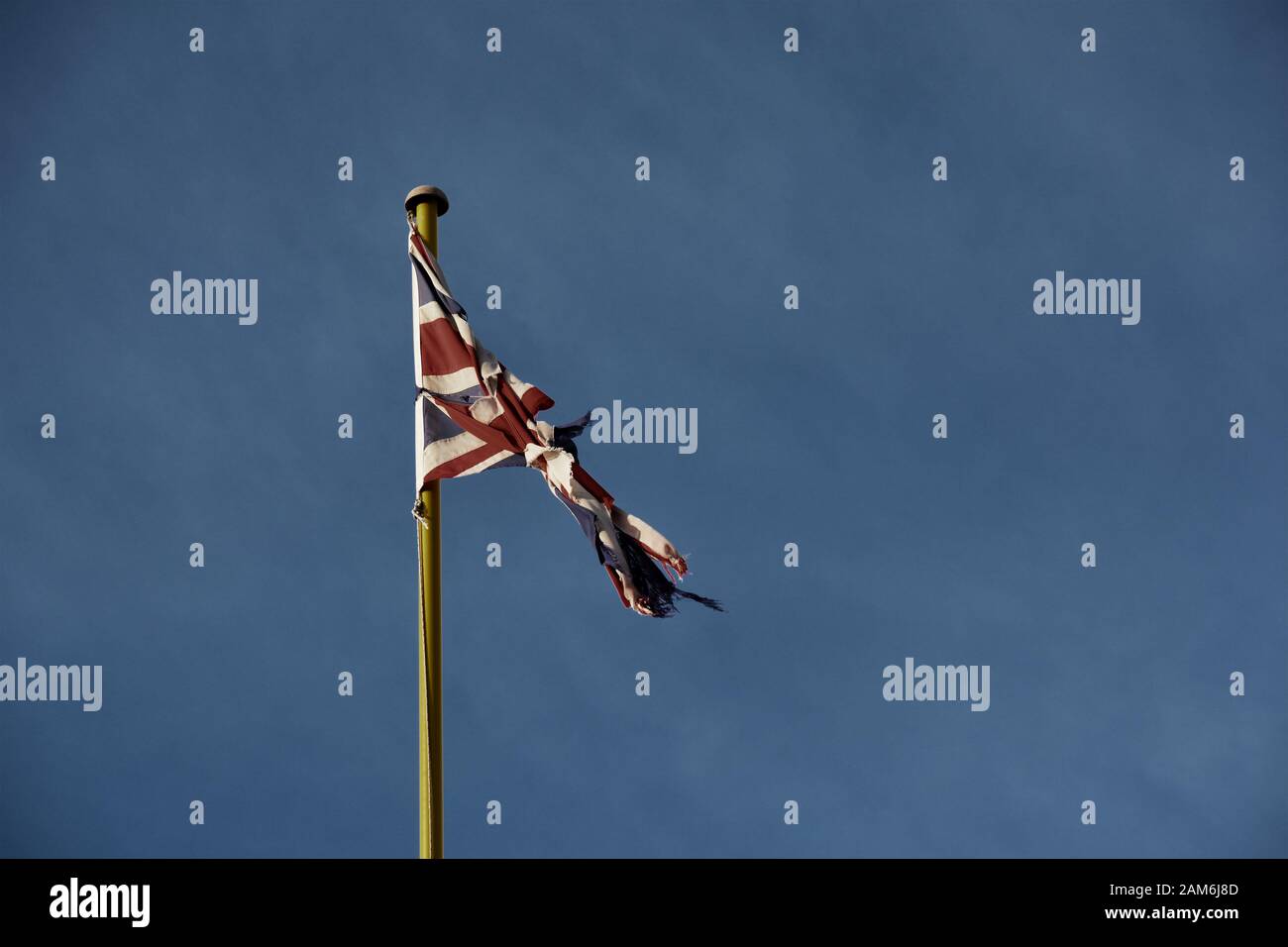 Una bandiera dell'Unione del Regno Unito vecchia, logora e lusingata, o la bandiera dell'Unione Jack fissata contro un cielo blu Foto Stock