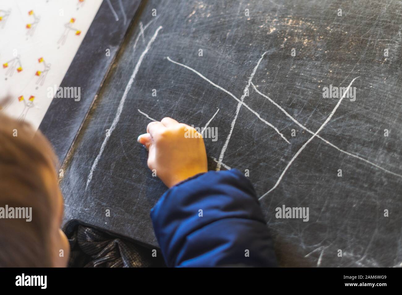 La mano di un bambino che disegna su una lavagna con gesso Foto Stock