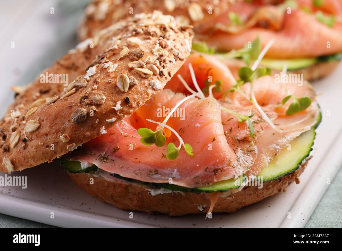 Due panini focacce con sale a fette di salmone, crema di formaggio, cetriolo, e micro verdi closeup Foto Stock