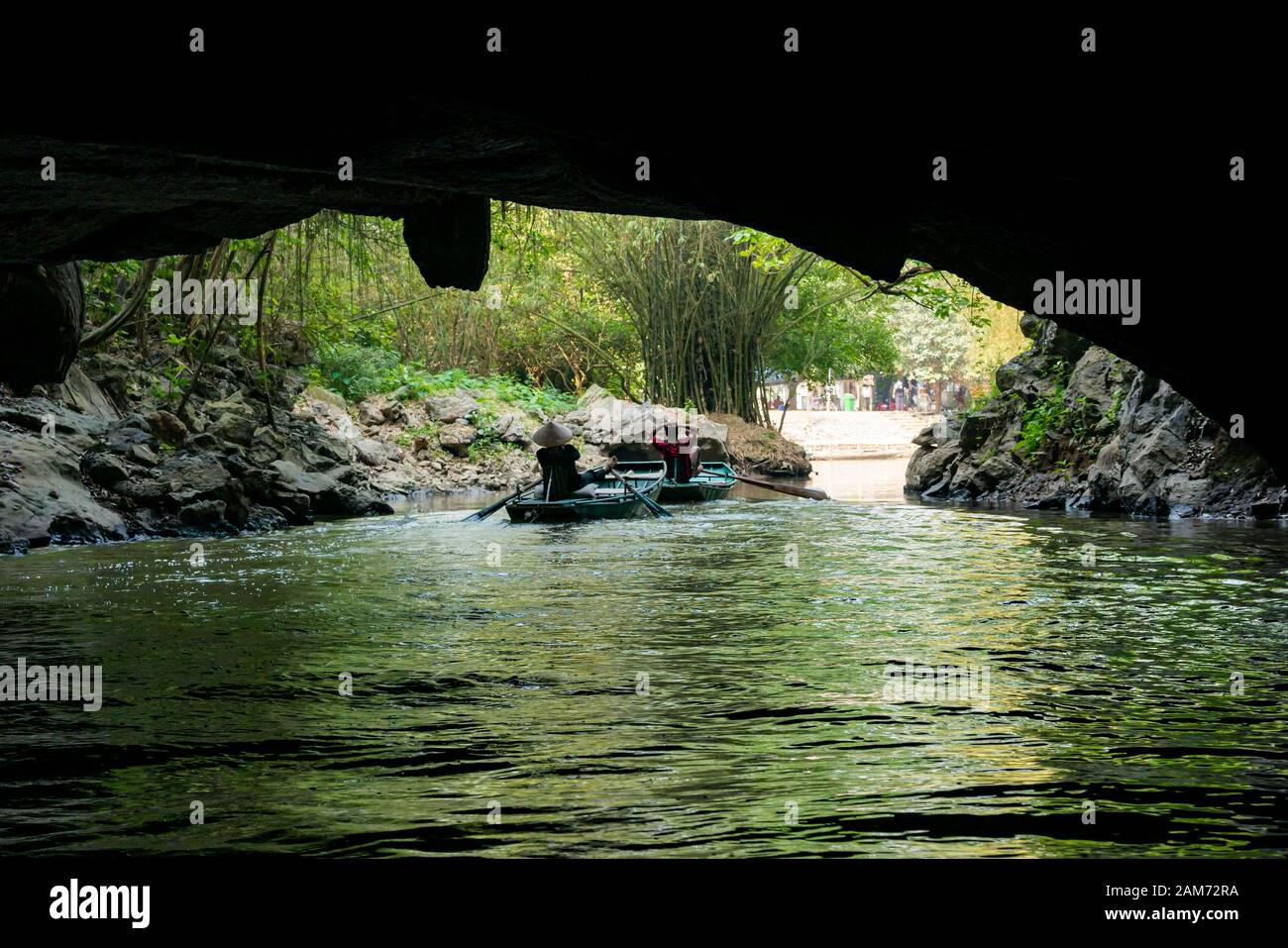 Locale uomo e donna canottaggio sampan con i piedi sul fiume attraverso caverna, Tam Coc grotta sistema, Ninh Binh, Vietnam, Asia Foto Stock