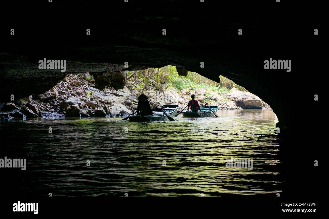 Locale uomo e donna canottaggio sampan con i piedi sul fiume attraverso caverna, Tam Coc grotta sistema, Ninh Binh, Vietnam, Asia Foto Stock