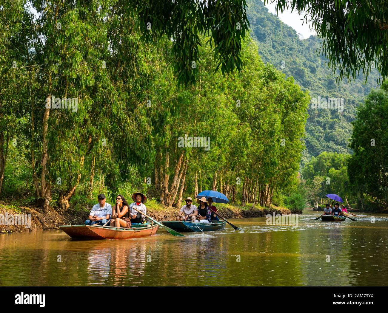 Turisti in sampan girati da locali asiatici canottaggio con i piedi, Tam Coc, Ninh Binh, Vietnam, Asia Foto Stock