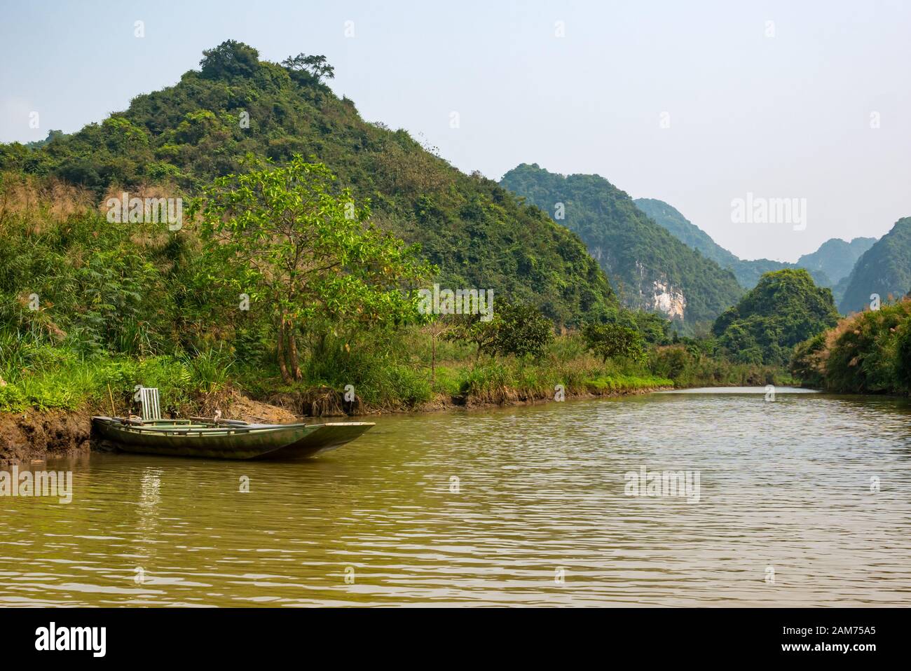 Sampan ormeggiato sul fiume con vista delle montagne carsiche calcaree, Ninh Binh, Vietnam, Asia Foto Stock