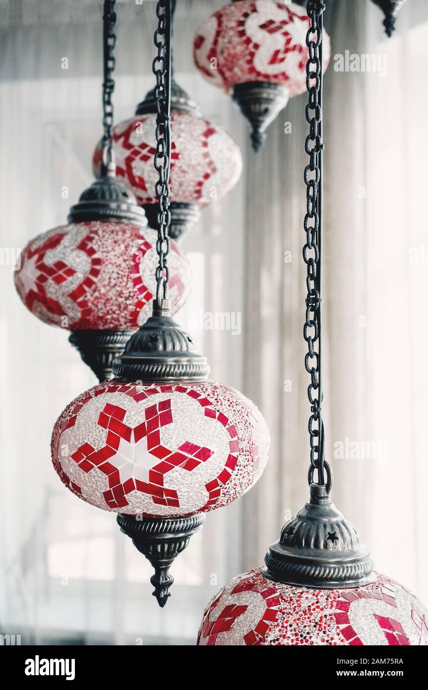 Primo piano di un lampadario di cristallo, fuoco selettivo e sfocatura intenzionale. Lampada di vetro multicolore con pendente turco, realizzata in fondali di luce rossa e bianca Foto Stock