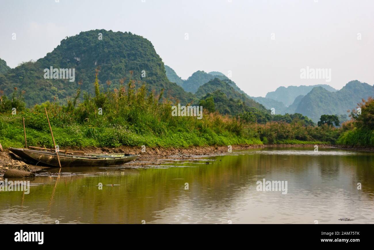 Sampan ormeggiato sul fiume con vista delle montagne carsiche calcaree, Ninh Binh, Vietnam, Asia Foto Stock