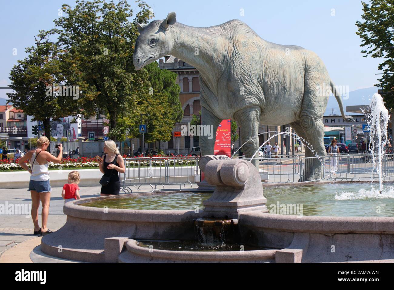 Bergamo, Italia - 05 agosto 2018: persone che fanno la foto con la statua di dinosauro nei pressi della stazione ferroviaria principale. Centenario della scienza naturale Mu Foto Stock
