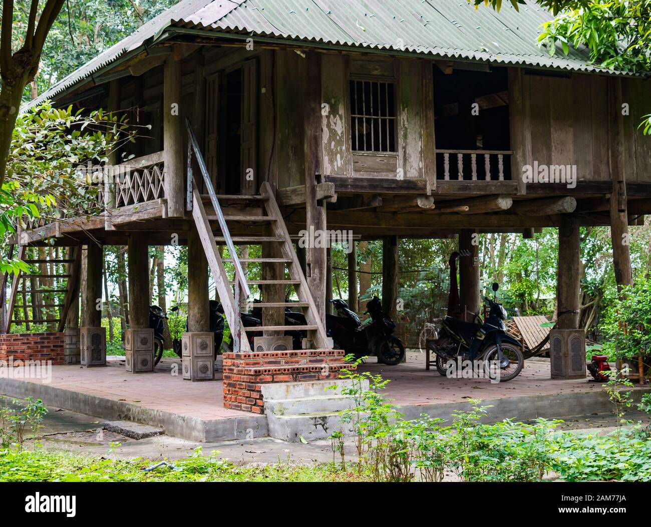 Tradizionale vecchia casa in legno su palafitte con moto parcheggiata sotto, Dong Tham, Ninh Binh, Vietnam, Asia Foto Stock