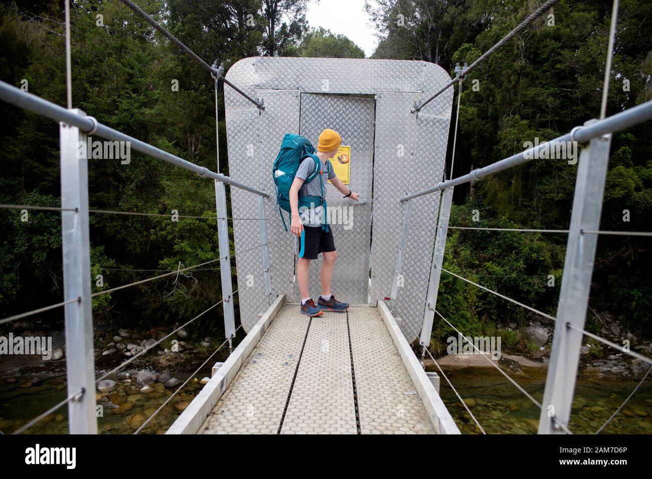 Camminando lungo il sentiero Old Ghost Road, Lyell fino a Seddonville, Nuova Zelanda. Porta ponte di prova Possum sul ponte pedonale sopra il ramo sud del fiume Mokinhinui Foto Stock