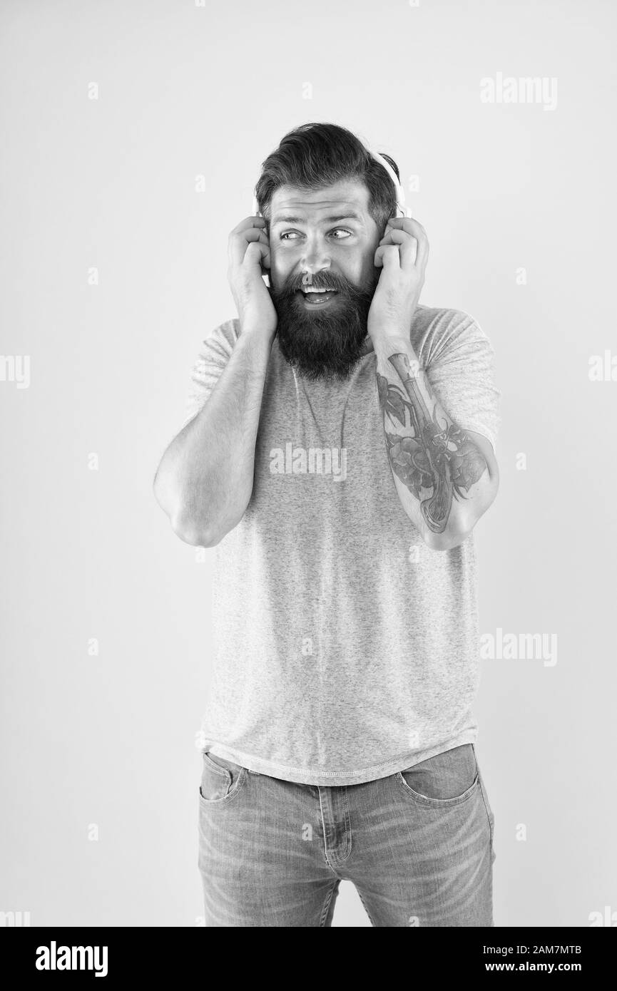 Mettere la cuffia sul. Uomo Barbuto ascoltare la musica in cuffia stereo. Hipster indossare cuffie regolabili sfondo giallo. Brutale guy utilizzare cuffie wireless bluetooth. La nuova tecnologia. Foto Stock