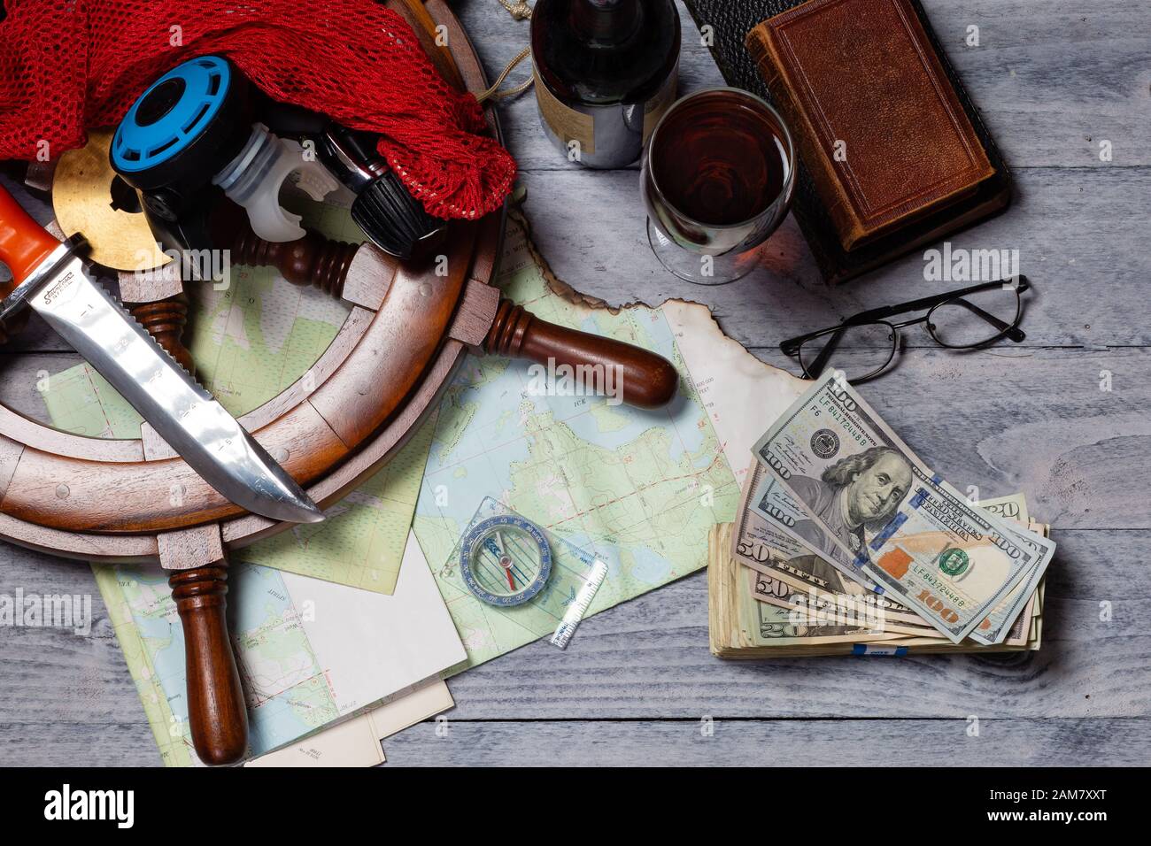 Mappa, bussola, vino, denaro, libri, ruota per nave, bicchieri, coltello e attrezzature per immersioni subacquee, pronti per un concetto di viaggio Foto Stock