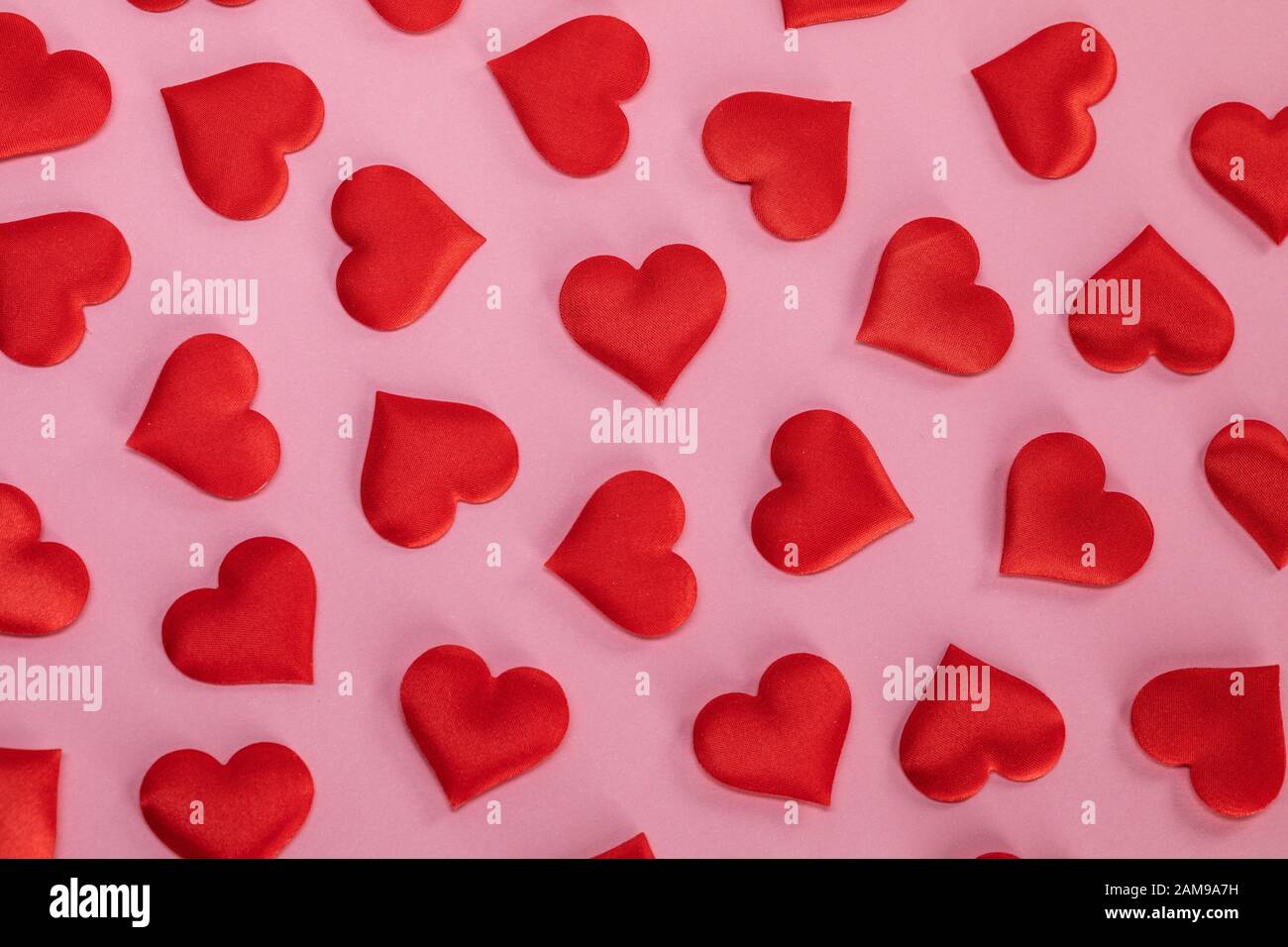 San Valentino molti cuori di seta rossa su sfondo di carta rosa, concetto di amore Foto Stock