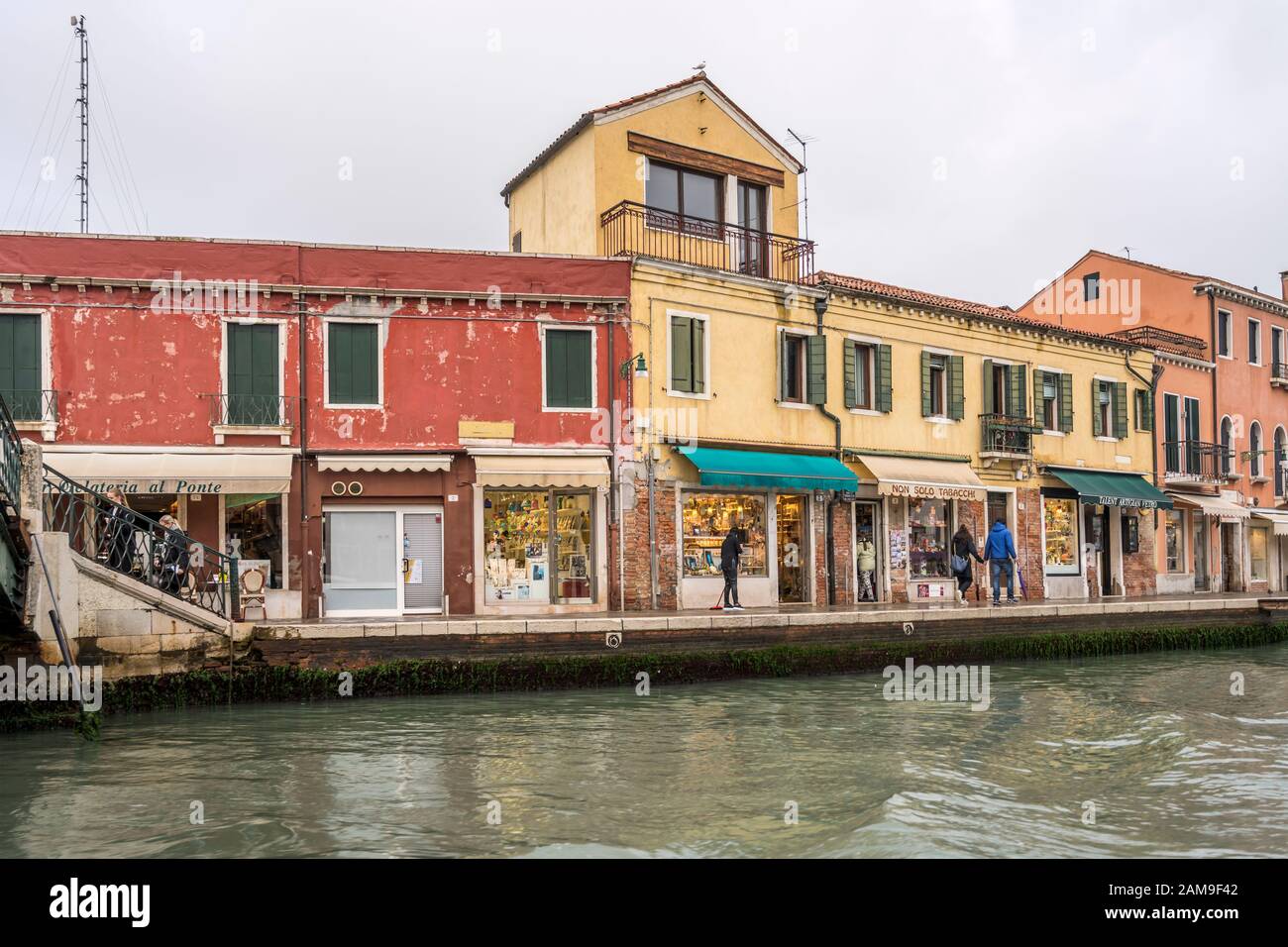 Venezia, ITALIA - 29 ottobre 2019: Paesaggio urbano con vecchie case e negozi sul lungofiume dei canali, girato il 29 ottobre 2019 in luminosa luce autunnale torbida a Muran Foto Stock