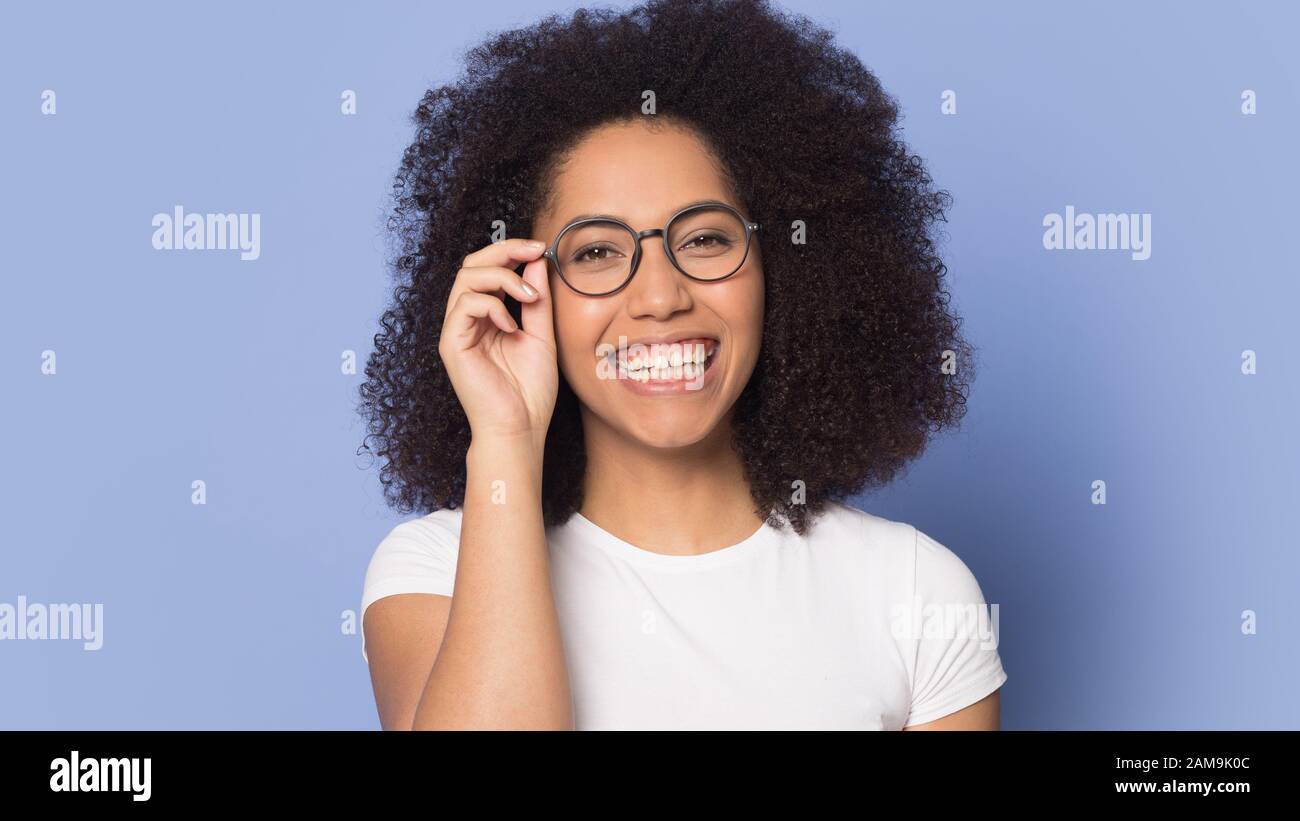 Felice ridere africano americano millennial ragazza che regola gli occhiali. Foto Stock