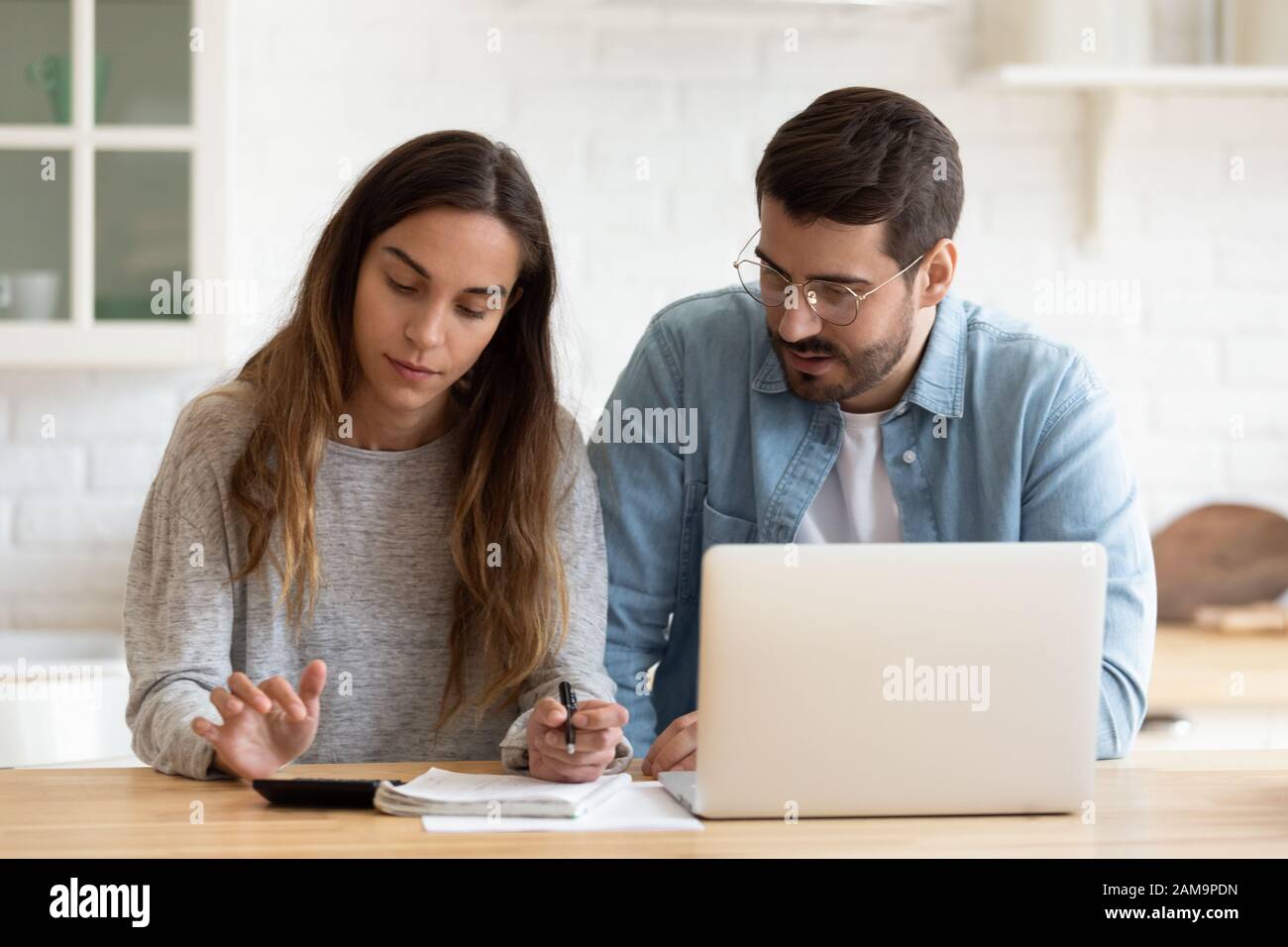 Concentrato giovane sposato coniuge calcolo mensile bilancio familiare insieme. Foto Stock