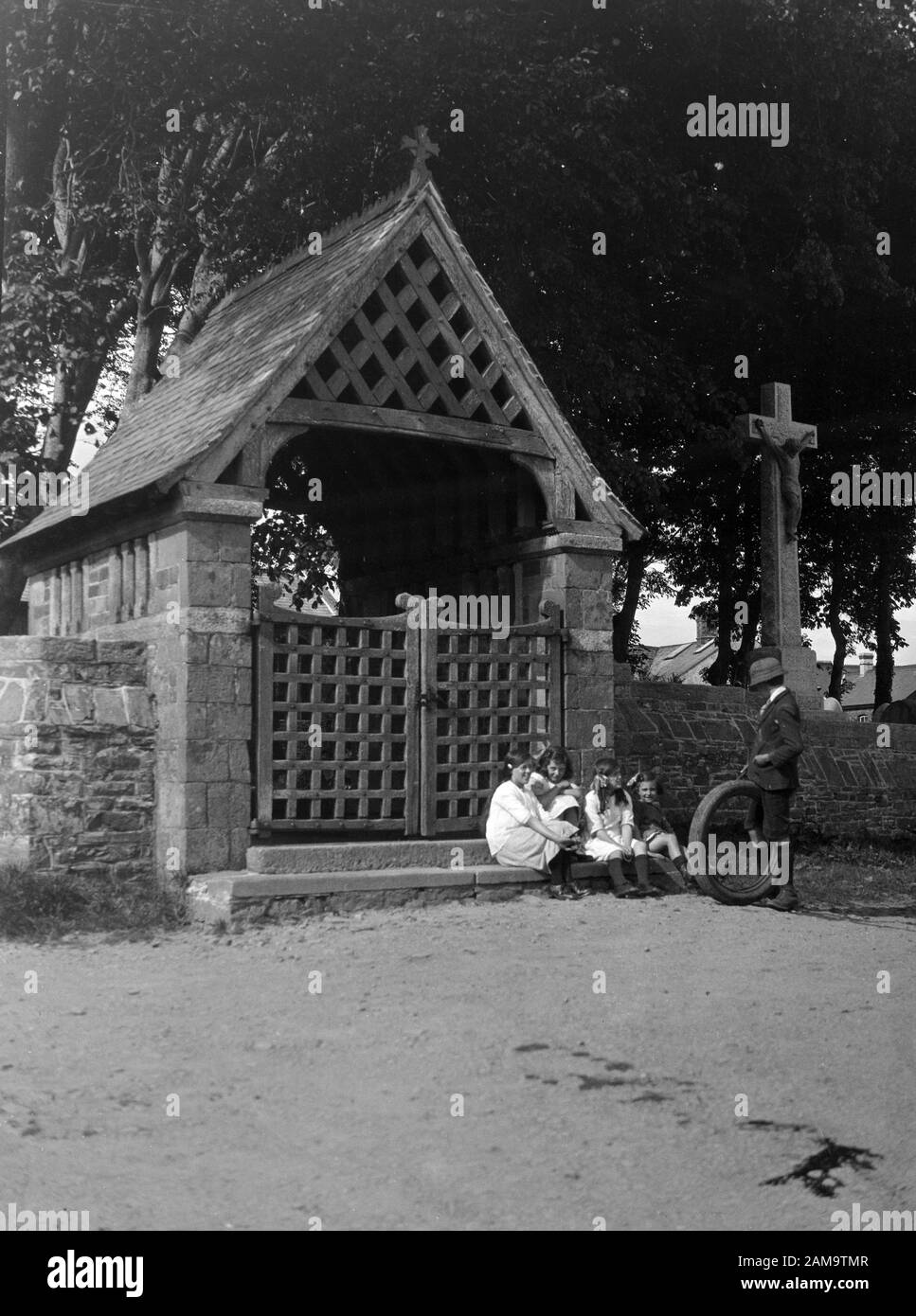 Archivio immagine circa 1920s di bambini che giocano con un vecchio pneumatico fuori St James la Grande chiesa, Kilkhampton, Cornovaglia, Regno Unito. Scansione da negativo originale. Foto Stock