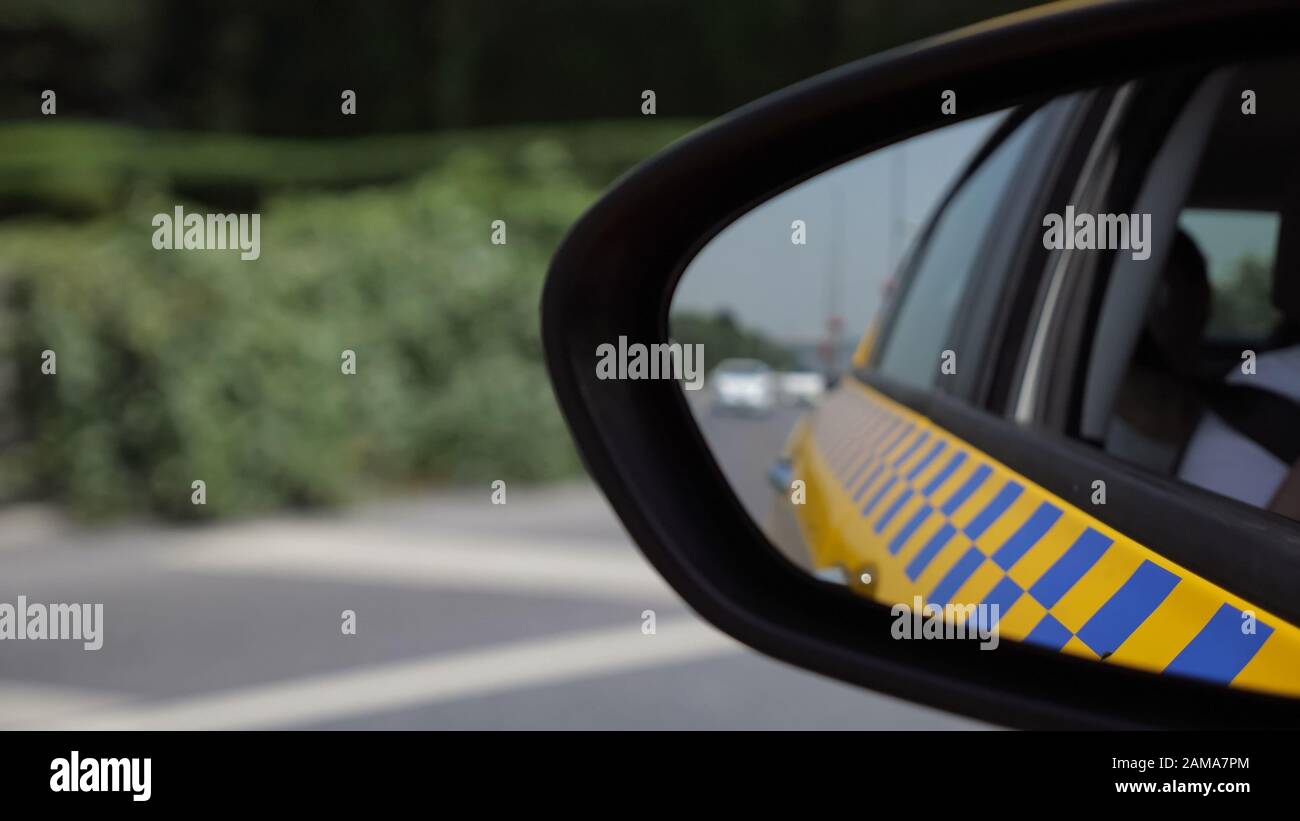 il traffico delle automobili sul ponte contro la vista sfocata del mare nello specchio di sinistra del veicolo del taxi closeup estremo Foto Stock