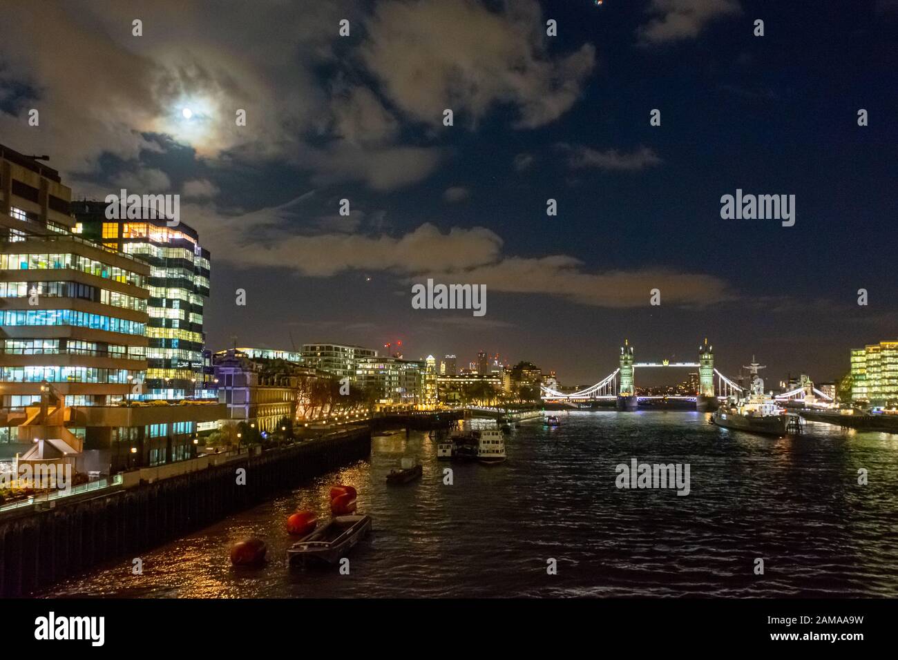 Guardando a est dal London Bridge lungo il Tamigi verso il Tower Bridge di notte con la luna sopra, Londra Foto Stock